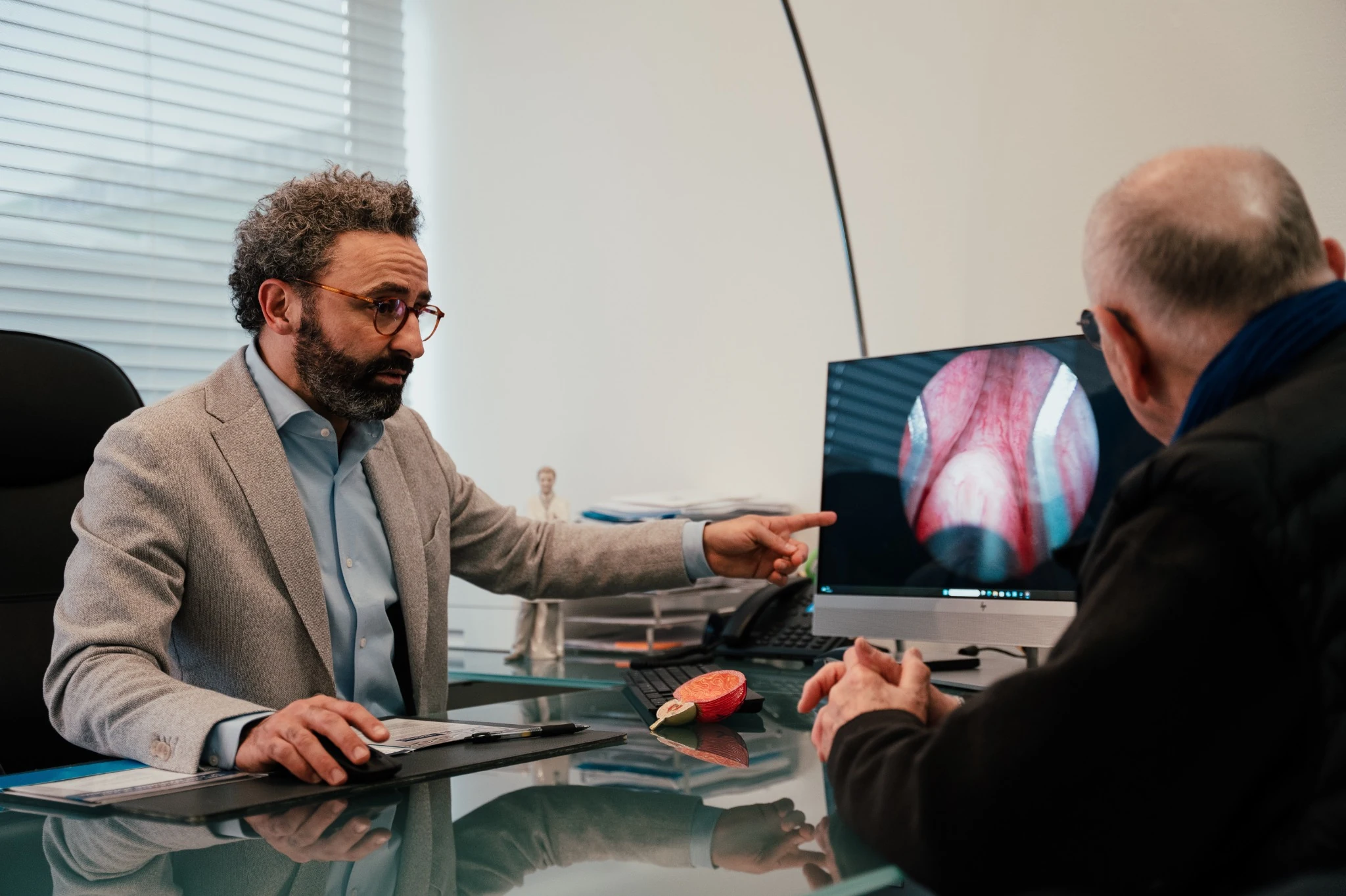 Un urologue explique des images à un patient en consultation.
